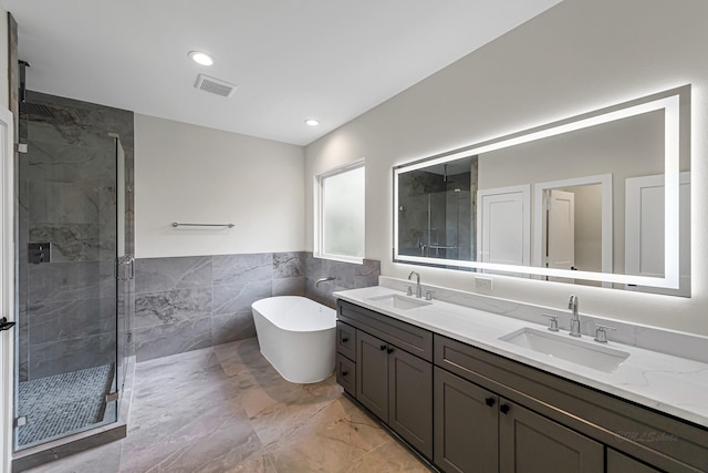 4224 Buck St, Houston, TX 77020 - bathroom with marble look tile flooring, tile walls, a shower stall, double vanity, and a freestanding bath