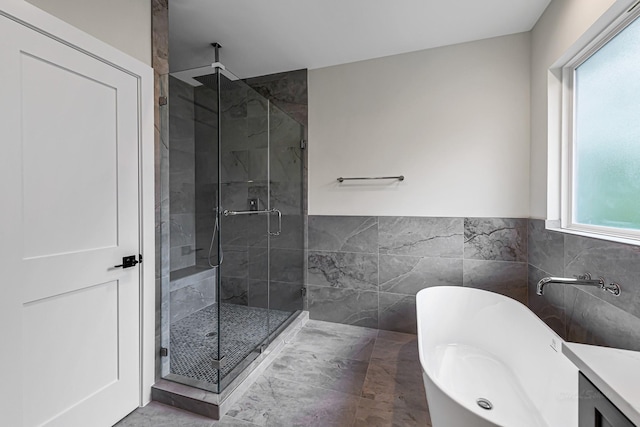 4224 Buck St, Houston, TX 77020 - bathroom featuring tile walls, a stall shower, a soaking tub, and a wainscoted wall
