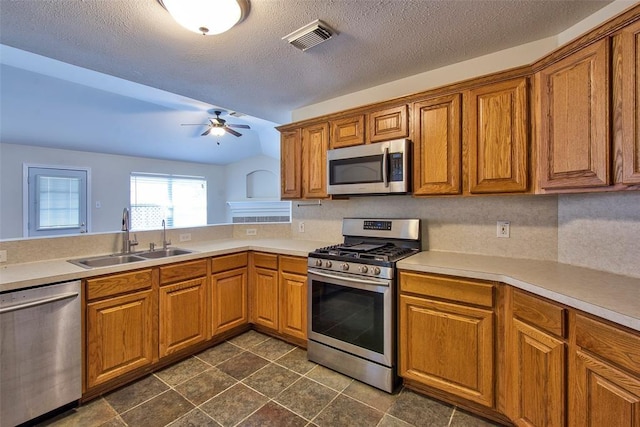 19511 Ingham Dr, Katy, TX 77449 - kitchen featuring stainless steel appliances, a sink, ceiling fan, brown cabinetry, and a textured ceiling