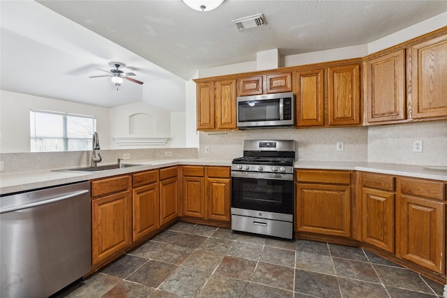 19511 Ingham Dr, Katy, TX 77449 - kitchen featuring appliances with stainless steel finishes, brown cabinets, ceiling fan, and tasteful backsplash
