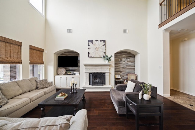 8718 Stowe Creek Ln, Missouri City, TX 77459 - living room featuring a towering ceiling, hardwood / wood-style flooring, a tiled fireplace, arched walkways, and baseboards