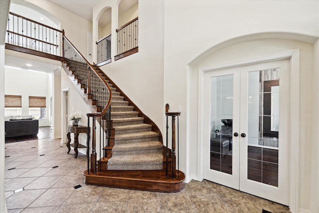 8718 Stowe Creek Ln, Missouri City, TX 77459 - stairs with french doors, a high ceiling, tile patterned floors, baseboards, and arched walkways