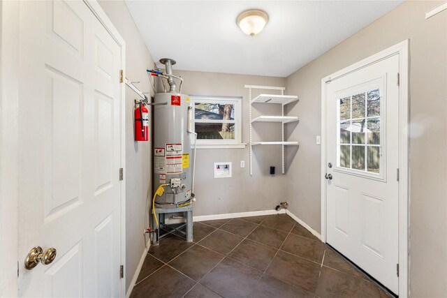 10134 Hanka Dr, Houston, TX 77043 - laundry area with gas water heater, dark tile patterned floors, baseboards, and washer hookup