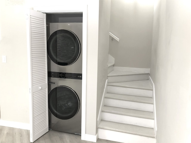 17202 Imperial Valley Dr Unit 16, Houston, TX 77060 - washroom featuring stacked washer / dryer, baseboards, and wood finished floors