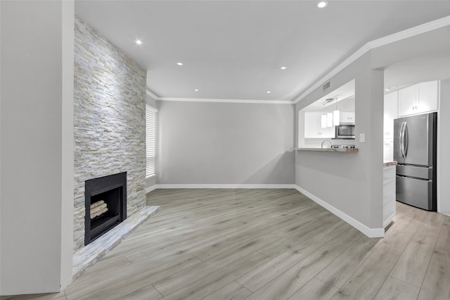17202 Imperial Valley Dr Unit 16, Houston, TX 77060 - unfurnished living room featuring light wood-style flooring, ornamental molding, baseboards, a stone fireplace, and recessed lighting