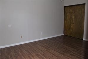 5122 Gladeside Dr, Katy, TX 77449 - unfurnished bedroom featuring dark wood-style floors, baseboards, and a closet
