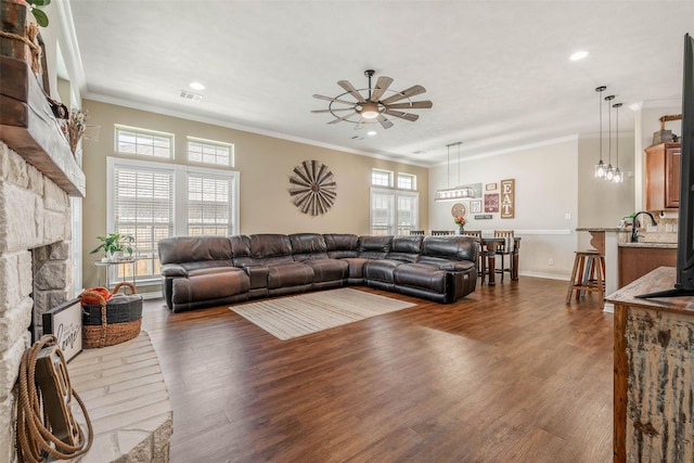 911 Dove Run Trl, College Station, TX 77845 - living room with a stone fireplace, healthy amount of natural light, ceiling fan, wood finished floors, and crown molding
