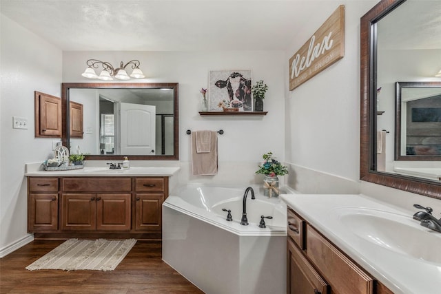 911 Dove Run Trl, College Station, TX 77845 - bathroom with two vanities, a garden tub, and wood finished floors