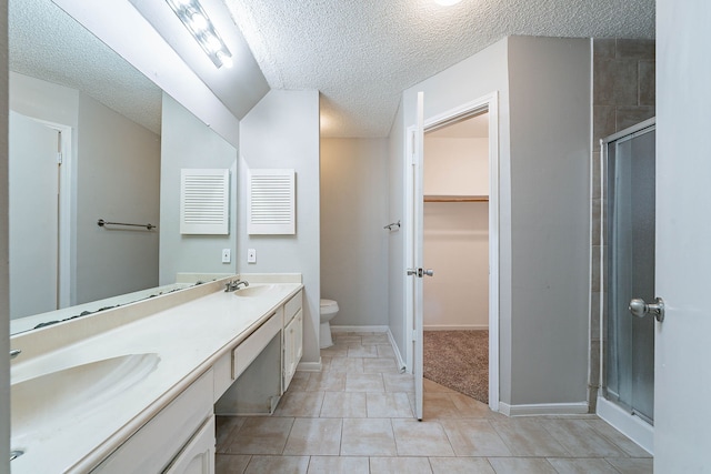 8006 Barnhill Dr, Humble, TX 77338 - bathroom with a textured ceiling, toilet, double vanity, a shower stall, and a walk in closet