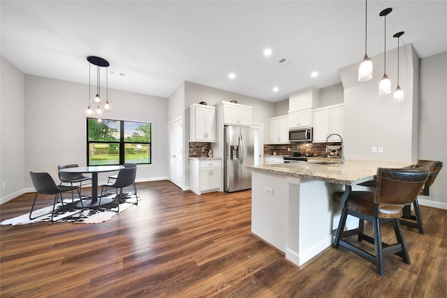 3148 Poe Dr, Montgomery, TX 77356 - kitchen with stainless steel appliances, a peninsula, dark wood finished floors, decorative backsplash, and light stone countertops