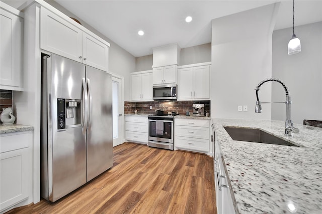 3148 Poe Dr, Montgomery, TX 77356 - kitchen with stainless steel appliances, a sink, white cabinetry, decorative backsplash, and light wood finished floors