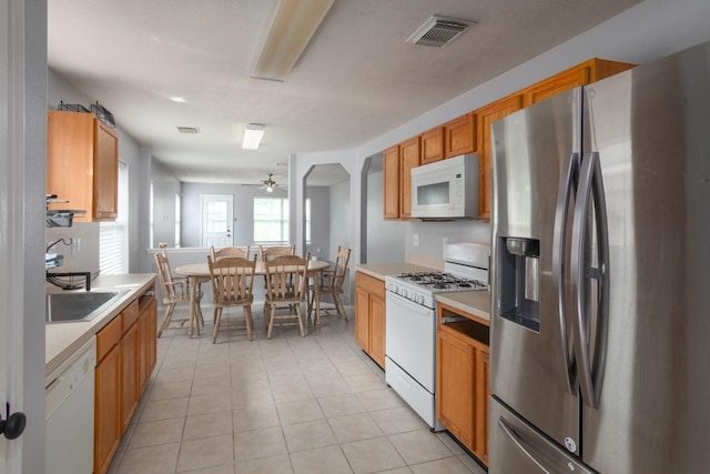 24027 Pinecreek Pt, Spring, TX 77373 - kitchen featuring white appliances, light tile patterned floors, light countertops, a ceiling fan, and brown cabinetry