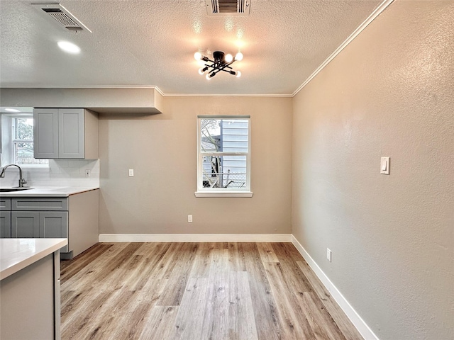 7845 Bonaire St, Houston, TX 77028 - unfurnished dining area featuring a sink, light wood finished floors, a textured ceiling, healthy amount of natural light, and crown molding