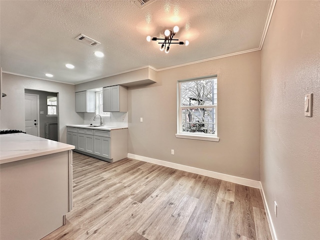 7845 Bonaire St, Houston, TX 77028 - kitchen featuring gray cabinetry, light wood-type flooring, baseboards, plenty of natural light, and a textured ceiling