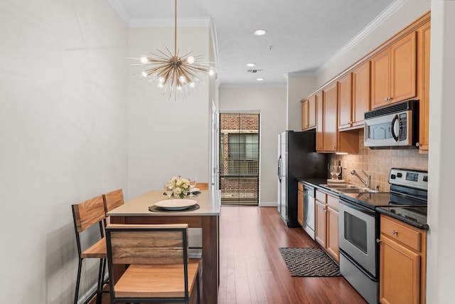 118 Mcgowen St Unit E, Houston, TX 77006 - kitchen featuring stainless steel appliances, a sink, a chandelier, crown molding, and decorative backsplash