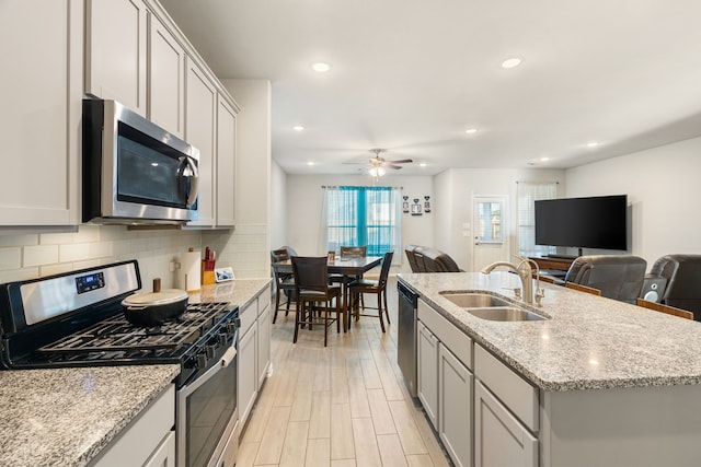 8219 Delta Down Dr, Fulshear, TX 77441 - kitchen with appliances with stainless steel finishes, a sink, open floor plan, a ceiling fan, and tasteful backsplash