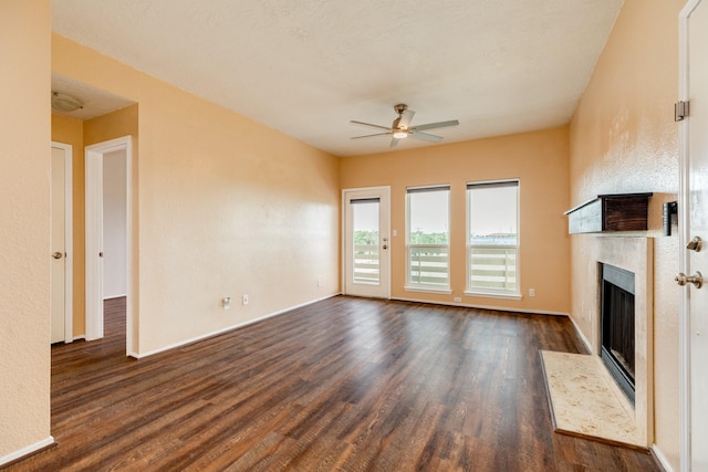 500 Ferry Rd Unit 434D, Galveston, TX 77550 - unfurnished living room with a high end fireplace, a ceiling fan, dark wood-style flooring, and baseboards