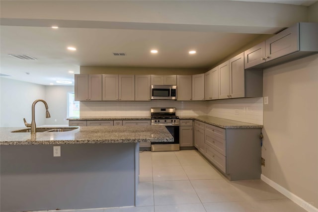 126 Red Ripple Rd, Houston, TX 77076 - kitchen with stainless steel appliances, a sink, gray cabinets, light stone countertops, and decorative backsplash