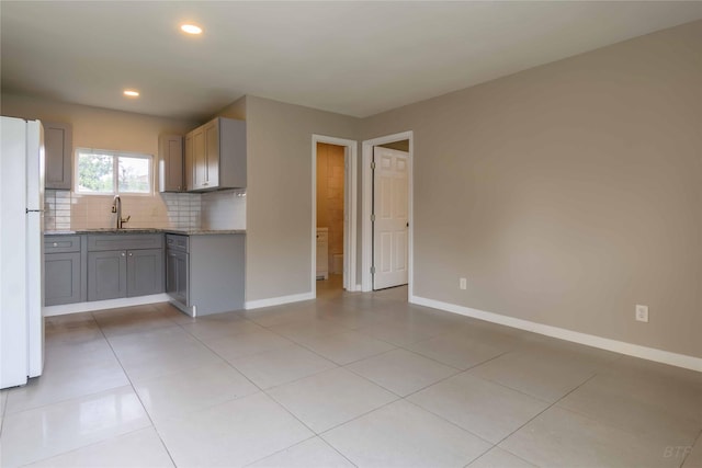 126 Red Ripple Rd, Houston, TX 77076 - kitchen featuring freestanding refrigerator, a sink, backsplash, gray cabinets, and baseboards