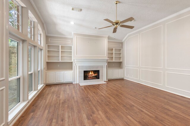 127 S Copperknoll Cir, The Woodlands, TX 77381 - unfurnished living room featuring a decorative wall, built in shelves, a fireplace, a textured ceiling, and wood finished floors