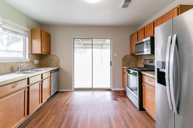 12518 Rosslare Dr, Houston, TX 77066 - kitchen with stainless steel appliances, a sink, light wood finished floors, and tasteful backsplash