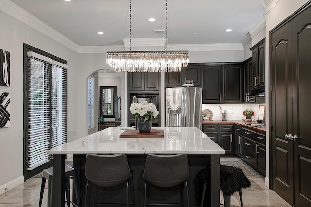 7 Heathcote Ct, The Woodlands, TX 77380 - kitchen featuring appliances with stainless steel finishes, arched walkways, a center island, decorative backsplash, and ornamental molding