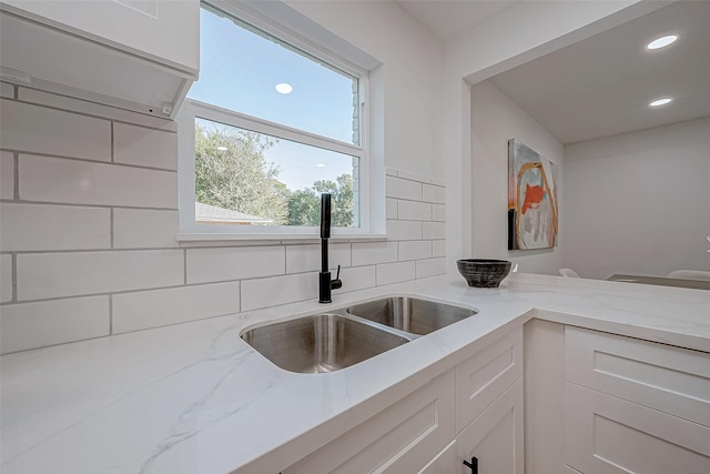 2414 Walnut Bend Ln, Houston, TX 77042 - kitchen with a sink, light stone counters, white cabinets, recessed lighting, and decorative backsplash