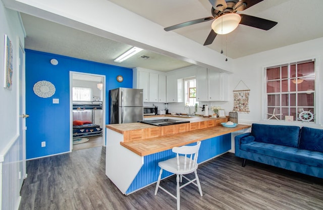 21735 Matagorda Dr, Galveston, TX 77554 - kitchen featuring wood counters, appliances with stainless steel finishes, white cabinets, and dark wood-style flooring