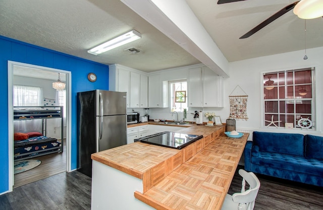 21735 Matagorda Dr, Galveston, TX 77554 - kitchen featuring stainless steel appliances, a sink, a peninsula, white cabinetry, and dark wood-type flooring