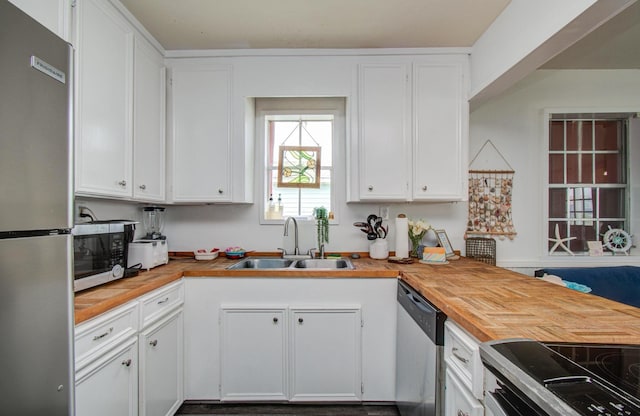 21735 Matagorda Dr, Galveston, TX 77554 - kitchen featuring appliances with stainless steel finishes, a sink, butcher block counters, and white cabinets