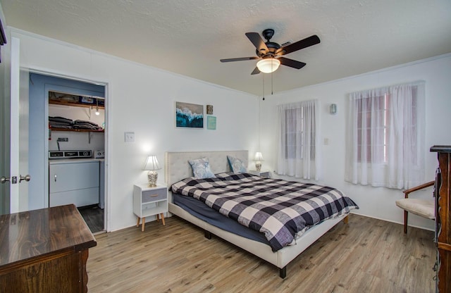 21735 Matagorda Dr, Galveston, TX 77554 - bedroom with washing machine and clothes dryer, light wood-type flooring, a ceiling fan, and a textured ceiling