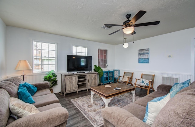 21735 Matagorda Dr, Galveston, TX 77554 - living room featuring a textured ceiling, wainscoting, a ceiling fan, and dark wood-style floors