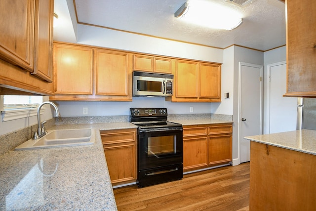 25635 Glen Loch Dr, Spring, TX 77380 - kitchen with stainless steel microwave, black range with electric stovetop, a sink, light wood finished floors, and light stone countertops