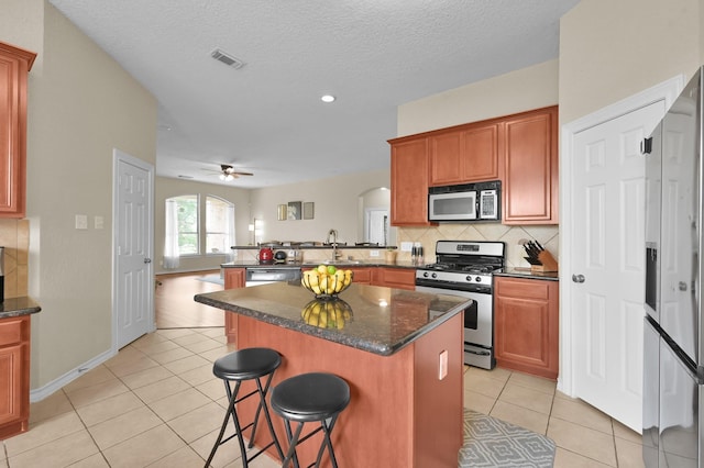 3307 Ellscott Ct, Spring, TX 77386 - kitchen with stainless steel appliances, arched walkways, a peninsula, light tile patterned flooring, and a textured ceiling