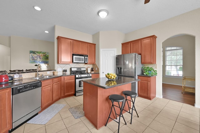 3307 Ellscott Ct, Spring, TX 77386 - kitchen featuring appliances with stainless steel finishes, arched walkways, a sink, a kitchen bar, and light tile patterned flooring