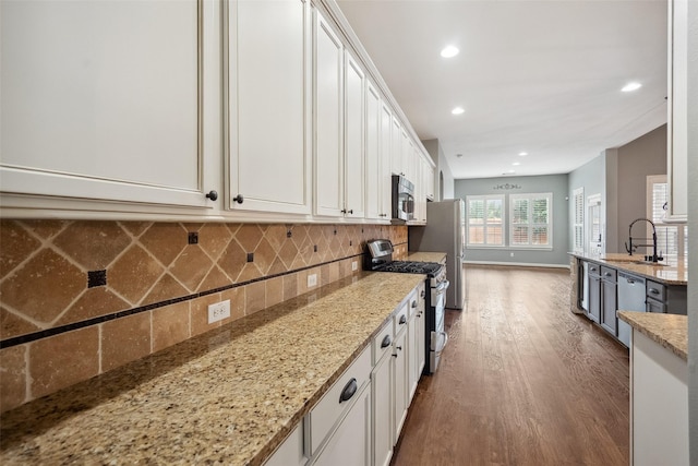2935 Red Maple Dr, Katy, TX 77494 - kitchen featuring stainless steel appliances, a sink, dark wood-style floors, white cabinets, and decorative backsplash