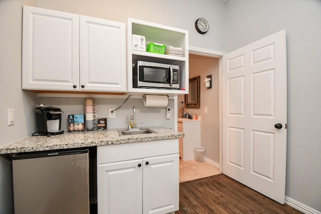 2935 Red Maple Dr, Katy, TX 77494 - kitchen with stainless steel microwave, a sink, refrigerator, white cabinetry, and dark wood-style floors