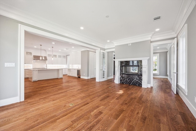 2216 Tangley St, Houston, TX 77005 - unfurnished living room featuring light wood-type flooring, crown molding, a premium fireplace, baseboards, and recessed lighting
