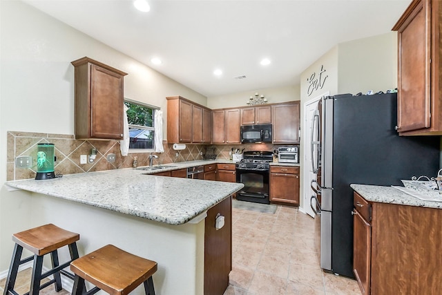 1703 Balsam Spruce Cir, Conroe, TX 77301 - kitchen featuring black appliances, a peninsula, a sink, decorative backsplash, and recessed lighting