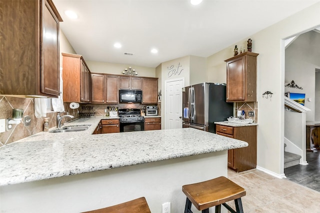 1703 Balsam Spruce Cir, Conroe, TX 77301 - kitchen with black appliances, a sink, a peninsula, backsplash, and light stone countertops