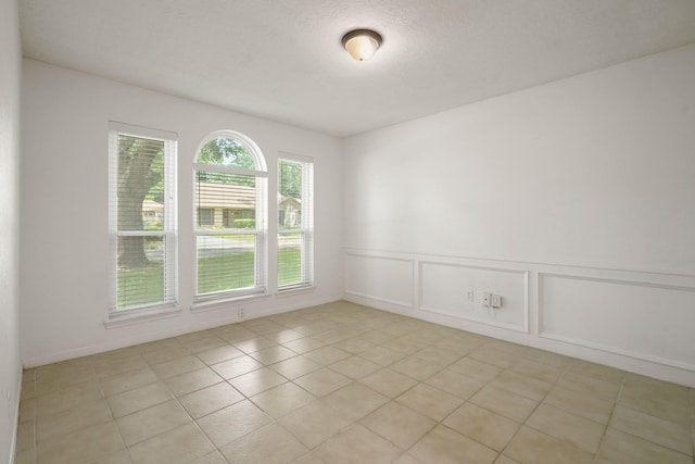 31111 Alice Ln, Tomball, TX 77375 - empty room featuring a decorative wall, light tile patterned floors, and a wainscoted wall