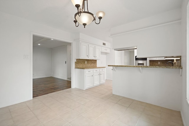 31111 Alice Ln, Tomball, TX 77375 - kitchen featuring oven, tasteful backsplash, dark stone counters, white cabinets, and light tile patterned floors