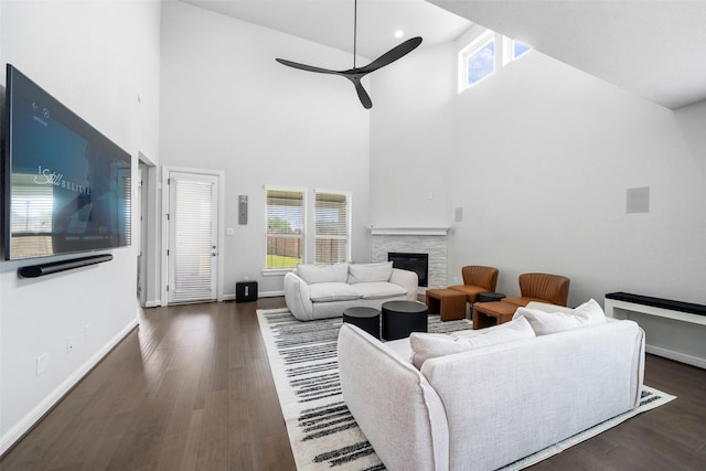 15838 Weston Ridge Dr, Humble, TX 77346 - living room featuring a ceiling fan, a high ceiling, a stone fireplace, wood finished floors, and baseboards
