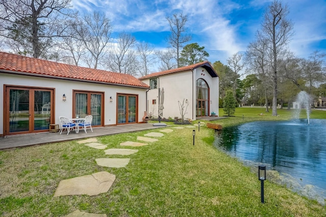 7519 Red Bay Cir, Magnolia, TX 77354 - back of property featuring french doors, stucco siding, a yard, a tiled roof, and a water view