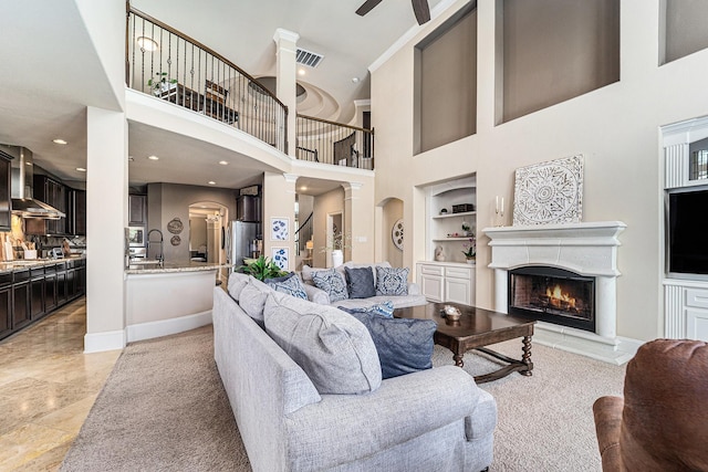 21806 W Firemist Ct, Cypress, TX 77433 - living room with built in shelves, a warm lit fireplace, a ceiling fan, a high ceiling, and arched walkways