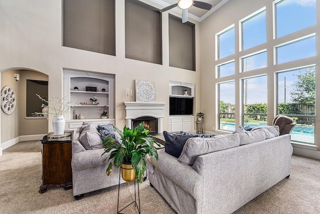 21806 W Firemist Ct, Cypress, TX 77433 - living room featuring carpet flooring, a towering ceiling, ceiling fan, crown molding, and baseboards