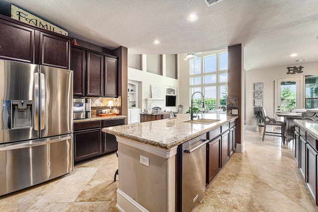 21806 W Firemist Ct, Cypress, TX 77433 - kitchen with appliances with stainless steel finishes, a sink, light stone countertops, a ceiling fan, and a textured ceiling