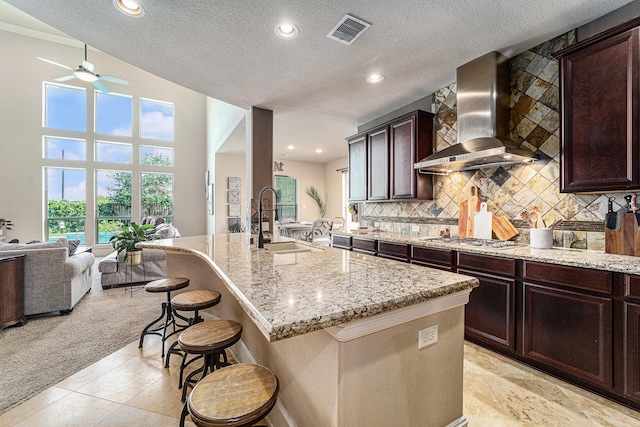 21806 W Firemist Ct, Cypress, TX 77433 - kitchen featuring wall chimney range hood, a sink, a ceiling fan, open floor plan, and stainless steel gas cooktop