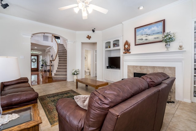11510 Maple Falls Dr, Tomball, TX 77377 - living area with built in features, ceiling fan, a tiled fireplace, light tile patterned floors, and ornamental molding