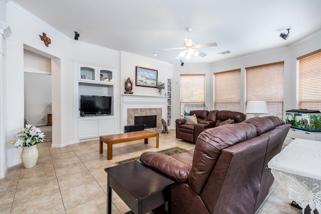 11510 Maple Falls Dr, Tomball, TX 77377 - living room featuring a ceiling fan, built in shelves, crown molding, light tile patterned floors, and a tile fireplace